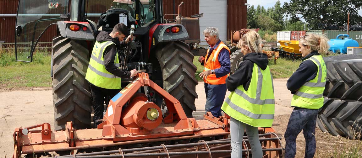 Roger Madge guides to young farmers on how to connect equipment to a tractor during a training session at Harper Adams University on July 7, 2023.