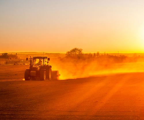 Sun sets as farmer finishes rolling a field. iStock.com/allou
